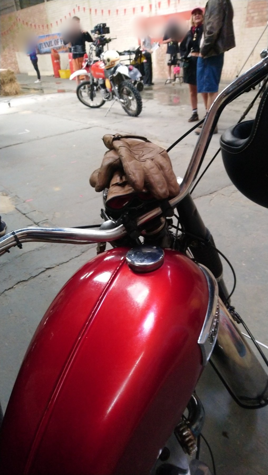 Close-up view over the red Triumph tank with gloves on the handlebars on a film set